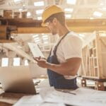 Male worker checking wooden plank at construction site