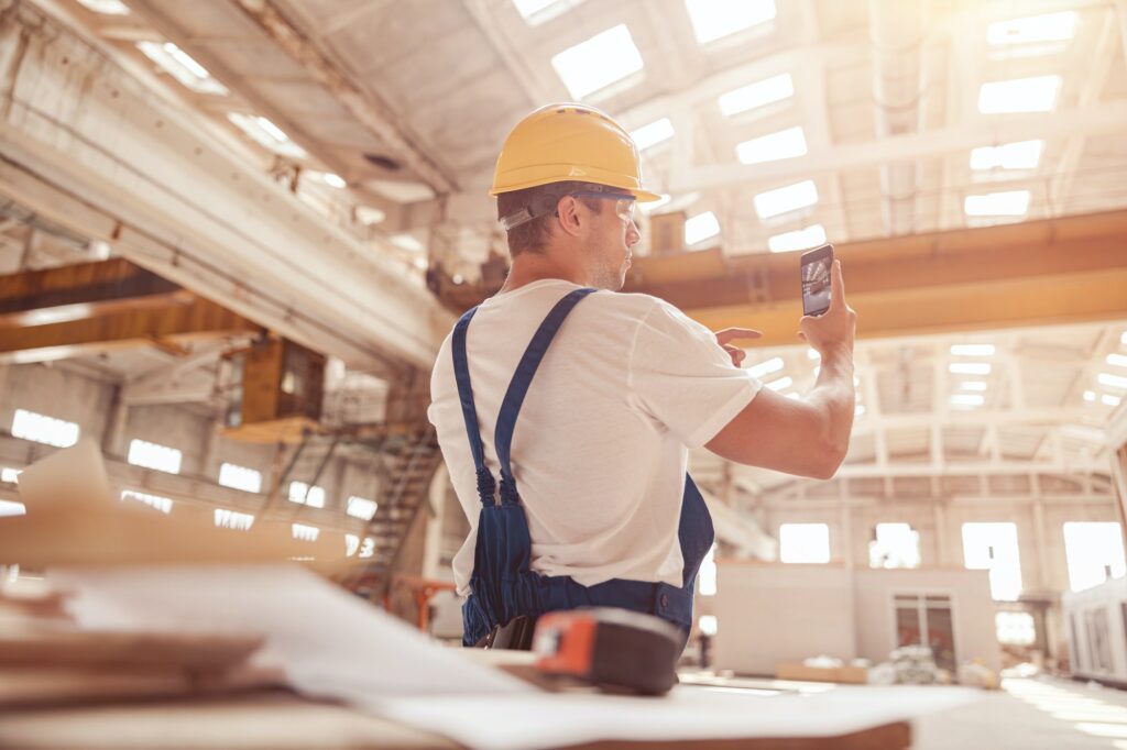 Male worker taking building photo with modern smartphone