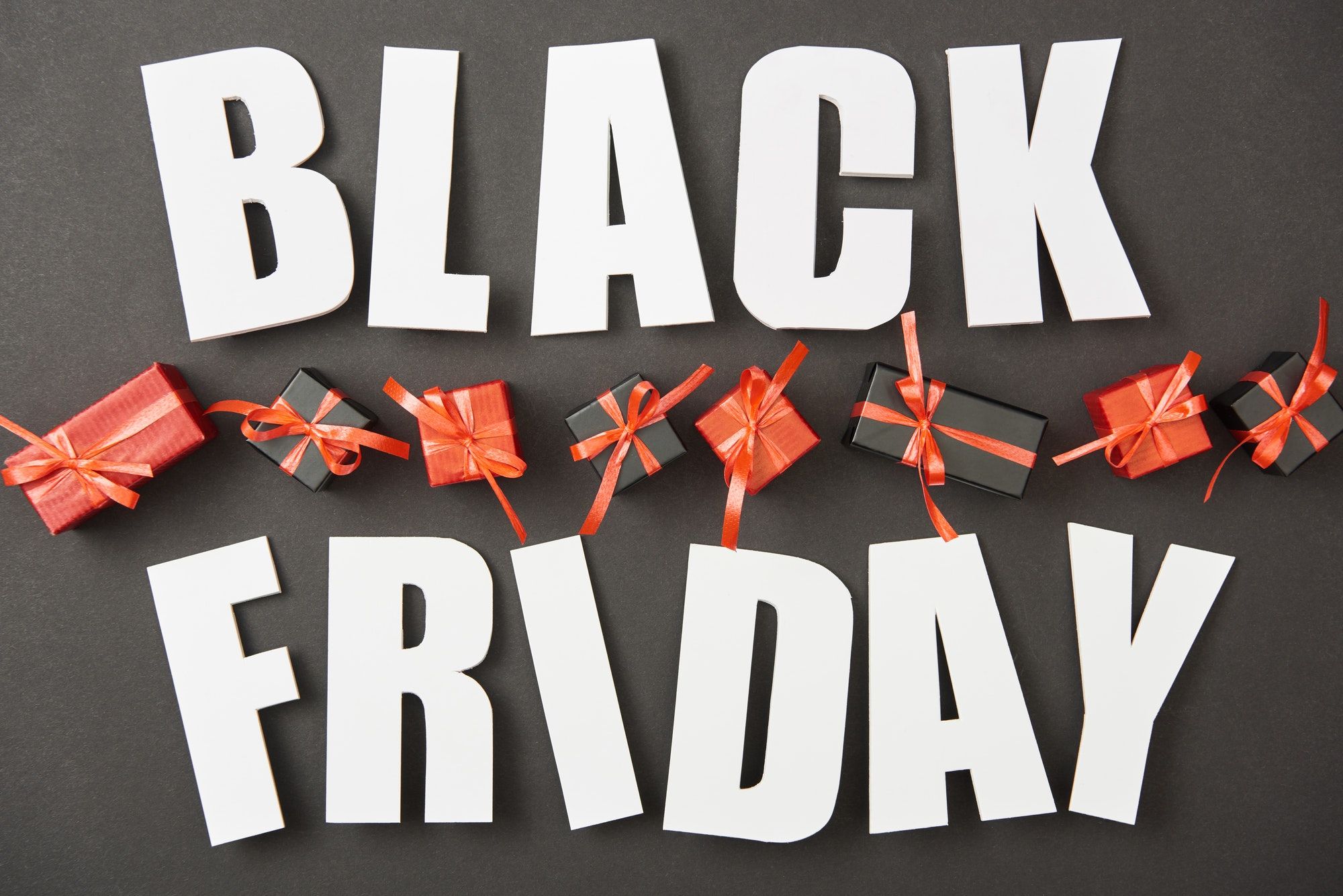 top view of black friday white lettering near presents on black background
